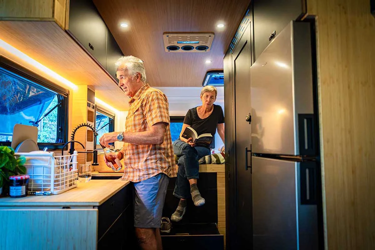 Couple inside a Geotrek Verus, one cooking and one reading on the bed