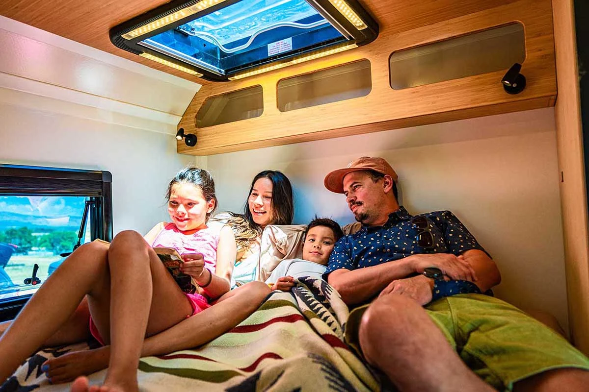 Family of four reading together on the bed in a Geotrek Verus
