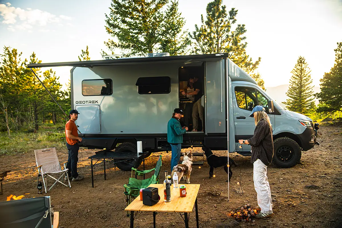 Friends and dogs setting up camp under the Fiamma awning of a Geotrek Verus