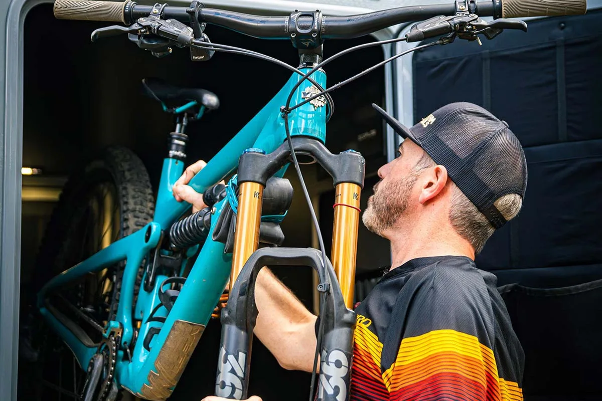 Man loading a mountain bike into the rear garage of a Geotrek Verus