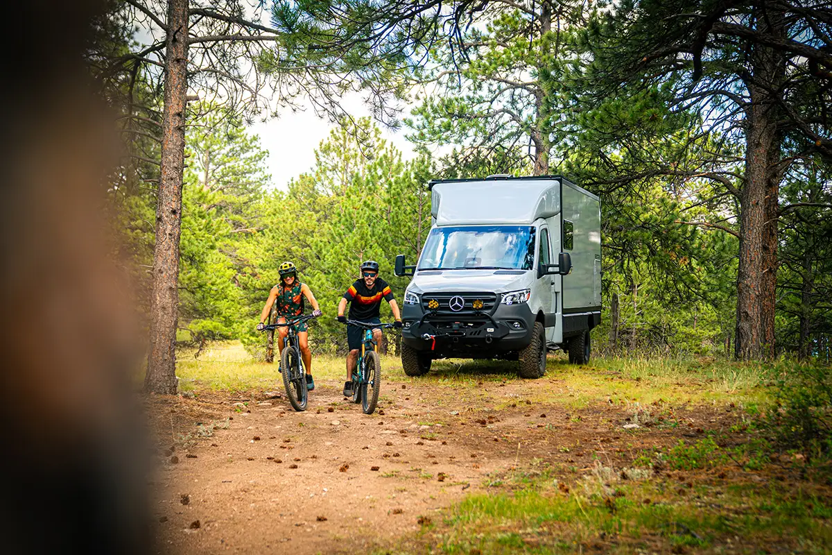 Two mountain bikers riding away from their parked Geotrek Verus