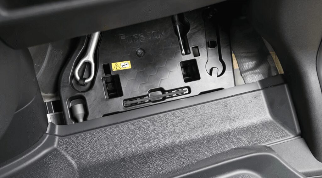Sprinter camper van toolkit compartment with lug wrench, jack handle, and screwdriver stored under the passenger seat