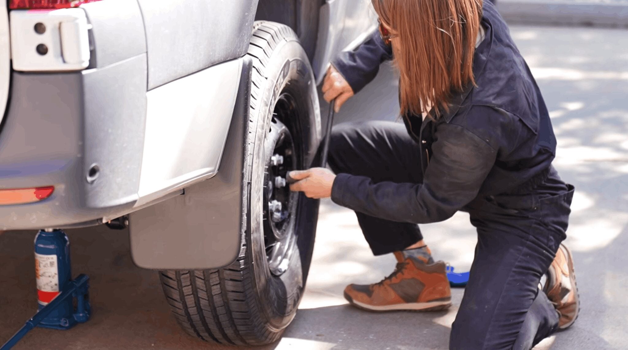 Loosening lug nuts on a Mercedes Sprinter camper van wheel with a lug wrench